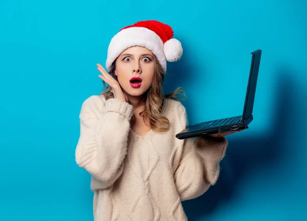 Schöne Frau mit Weihnachtsmütze und Laptop auf blauem Ba — Stockfoto