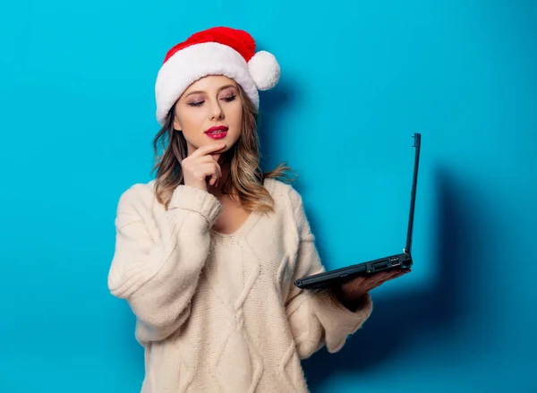 Bella donna in cappello di Natale con computer portatile su ba blu — Foto Stock