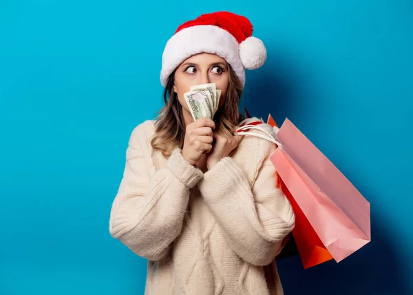 Hermosa mujer con bolsas de compras y reloj de dinero en backg azul —  Fotos de Stock