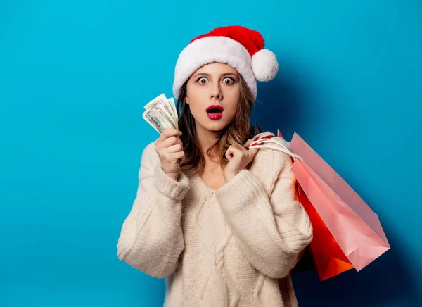 Beautiful woman with shopping bags and money clock on blue backg — Stock Photo, Image