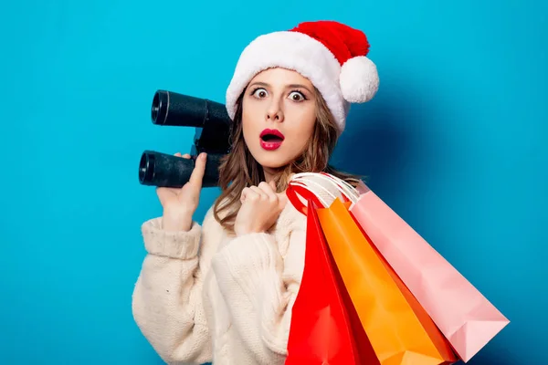 Beautiful woman with shopping bags and binoculars on blue backgr — Stock Photo, Image