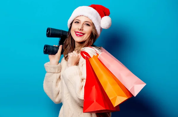 Beautiful woman with shopping bags and binoculars on blue backgr — Stock Photo, Image