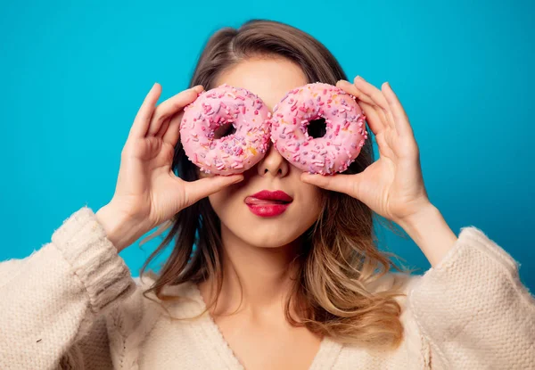 Stijl vrouw in trui met donut op blauwe achtergrond — Stockfoto