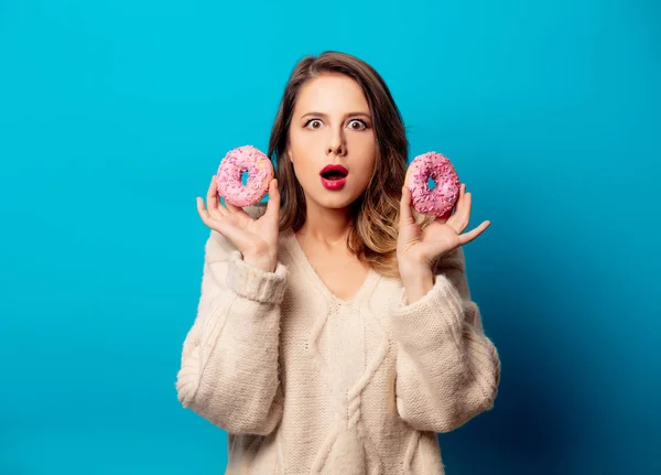 Mavi arka planda donutlu süveter giyen tarz bir kadın. — Stok fotoğraf