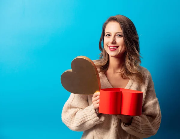 Mujer de estilo en suéter con caja de regalo sobre fondo azul — Foto de Stock