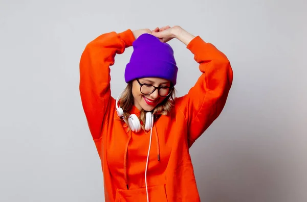 Stile ragazza con cappuccio arancione e cappello viola con cuffie — Foto Stock