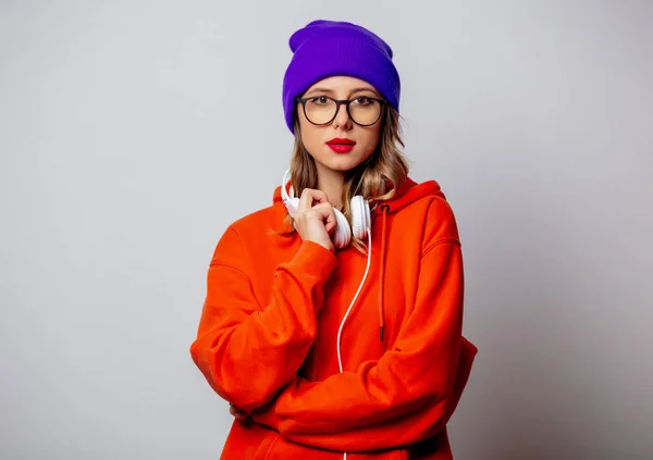 Stile ragazza con cappuccio arancione e cappello viola con cuffie — Foto Stock