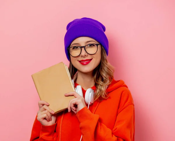 Stijl vrouw met koptelefoon en boeken op roze achtergrond — Stockfoto
