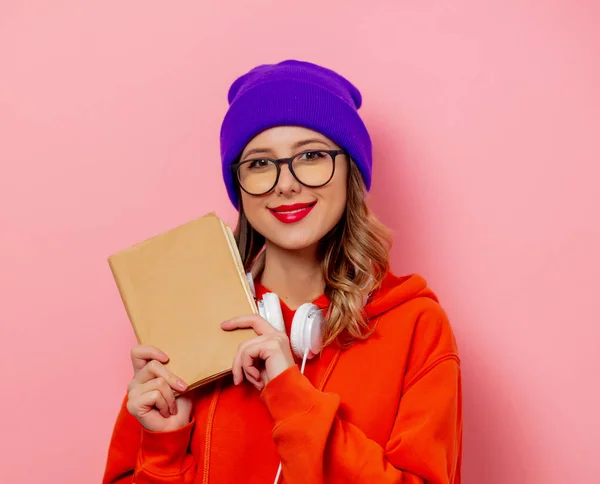 Estilo mulher com fones de ouvido e livros sobre fundo rosa — Fotografia de Stock