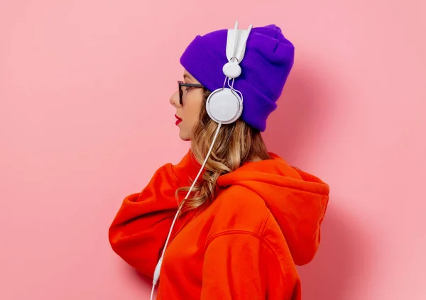 Stijl meisje in oranje hoodie en paarse hoed met hoofdtelefoon op pi — Stockfoto