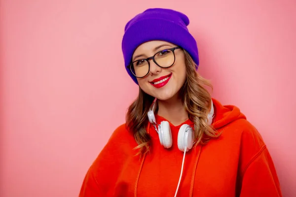 Chica de estilo en sudadera con capucha naranja y sombrero púrpura con auriculares en pi —  Fotos de Stock