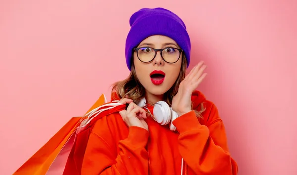 Estilo menina com capuz laranja e chapéu roxo com sacos de compras em — Fotografia de Stock