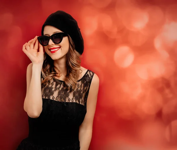 Stile donna in occhiali da sole e abito nero su sfondo rosso — Foto Stock