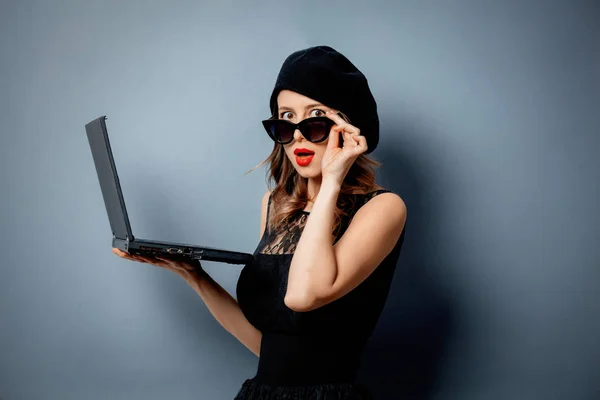 Jonge vrouw in zwarte jurk met notebook op grijze achtergrond — Stockfoto