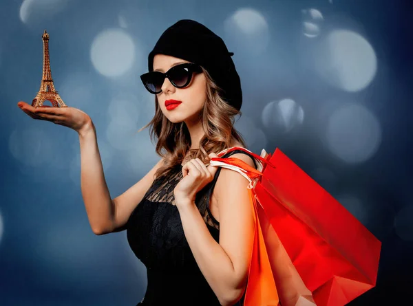 Mujer de estilo en gafas de sol con bolsas de compras sobre fondo gris —  Fotos de Stock