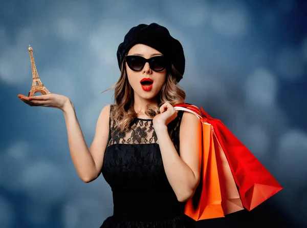 Style femme en lunettes de soleil avec des sacs à provisions sur fond gris — Photo