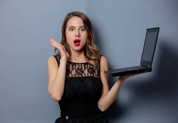 Jonge vrouw in zwarte jurk met notebook op grijze achtergrond — Stockfoto