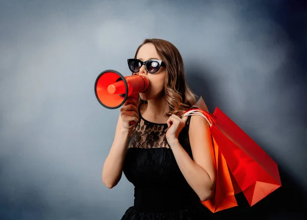 Style woman in sunglasses with shopping bags and louder on grey — Stock Photo, Image