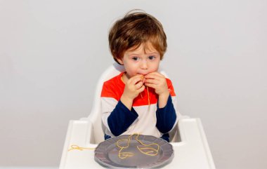 Küçük çocuk elleriyle spagetti yiyor.