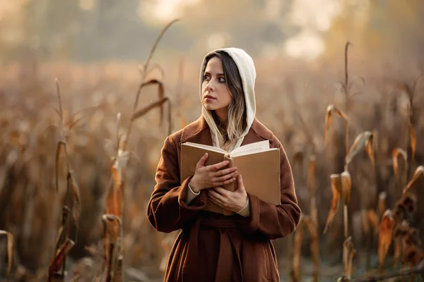 Stijl vrouw met boek op maïsveld in de herfst seizoen — Stockfoto