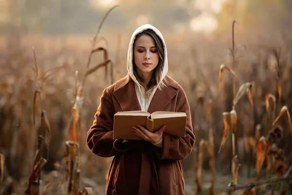 Mulher de estilo com livro no campo de milho na temporada de outono — Fotografia de Stock