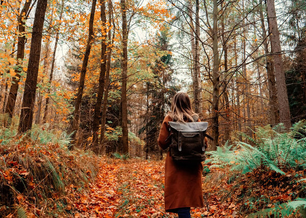 girl with a backpack in the autumn forest