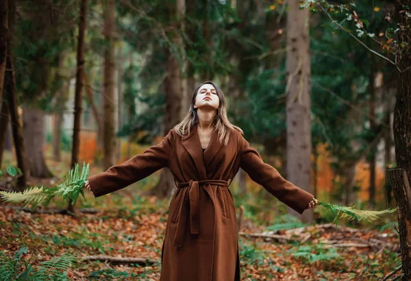 Mujer de estilo con rama de helecho en un bosque otoñal — Foto de Stock