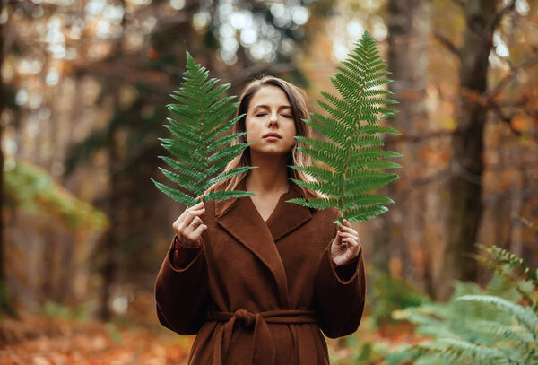 Style woman with fern branch in a autumn time forest