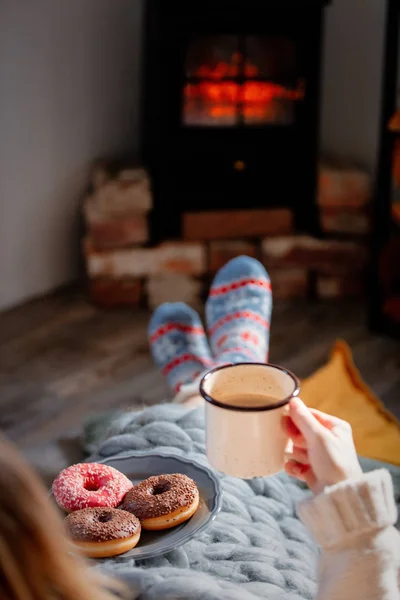 Fille avec une tasse de café et beignets près de la cheminée à la maison — Photo