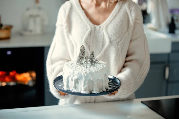 Woman holding christmas cake with cream on table at kitchen — Stock Photo, Image