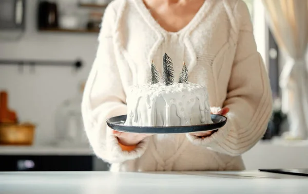 Mutfakta elinde kremalı Noel pastası tutan bir kadın. — Stok fotoğraf