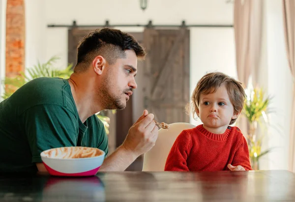 Мужчина кормит ребенка за столом в столовой — стоковое фото