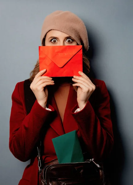 Young woman postman with red envelope on grey background — Stock Photo, Image