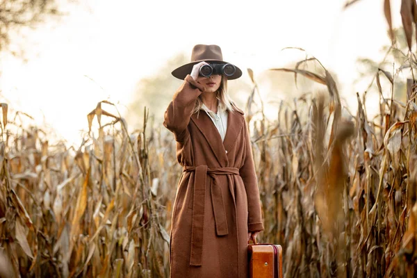 Estilo mulher com mala de viagem e binóculos no campo de milho em — Fotografia de Stock