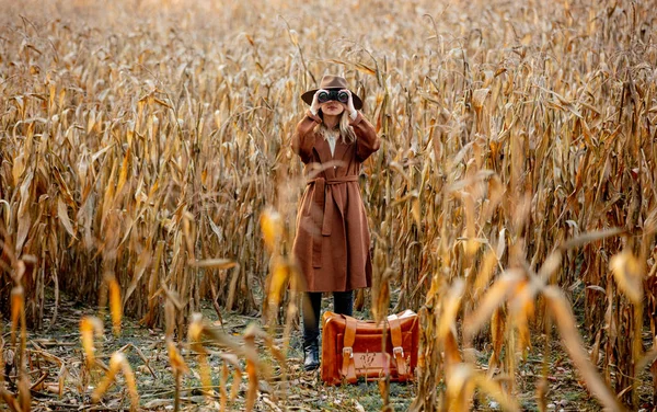 Femme de style avec valise de voyage et jumelles sur le champ de maïs dans — Photo