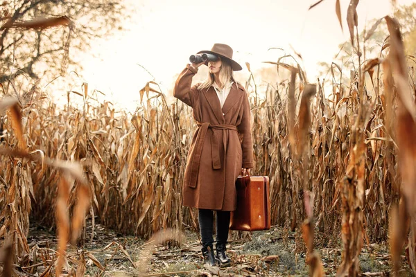 Stile donna con valigia da viaggio e binocolo su campo di mais in — Foto Stock