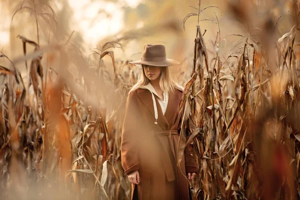Stile donna in cappotto e cappello sul campo di mais nella stagione autunnale — Foto Stock