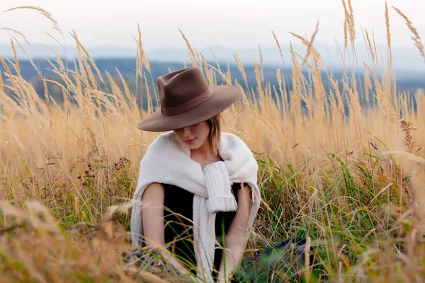 Mädchen im Pullover sitzt in gelbem Gras auf dem Land mit m — Stockfoto