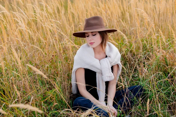 Stijl meisje in trui zit in geel gras op het platteland met m — Stockfoto