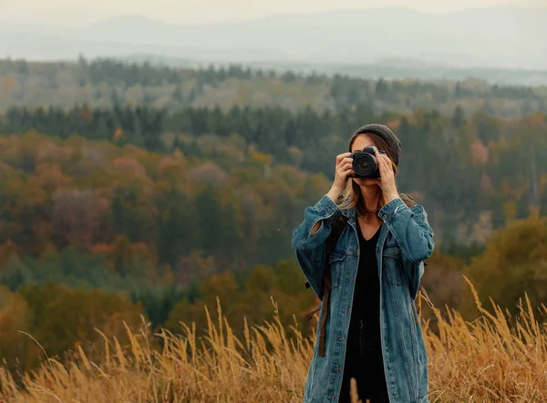 Stil flicka med kamera och ryggsäck på landsbygden med berg — Stockfoto
