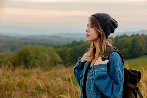 Chica de estilo en chaqueta de mezclilla y sombrero con mochila en el campo — Foto de Stock