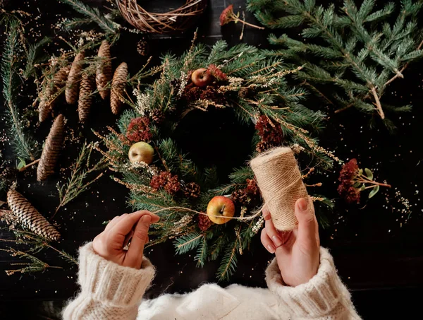 Жінка в білому светрі робить різдвяний вінок — стокове фото