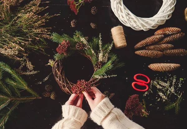 Woman in white sweater making a Christmas wreath — Stock Photo, Image