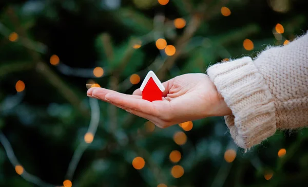 Woman holding little red house in hand on Christmas lights and f — Stock Photo, Image