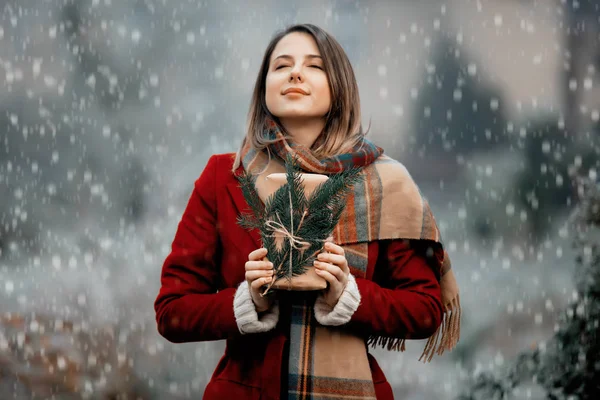 Femme en manteau rouge avec coffret cadeau dans la campagne enneigée — Photo