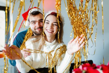 Noel şapkalı genç çift Noel için evi süslüyor.