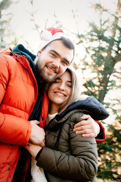 Romantic couple in Christmas hats near fir tree. — Stock Photo, Image