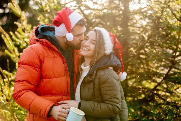 Романтическая пара в рождественских шляпах возле елки . — стоковое фото