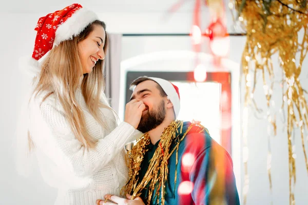 Unga par i julen hattar dekorerar huset till jul — Stockfoto