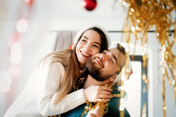 Giovane coppia in cappelli di Natale decora la casa per Natale — Foto Stock